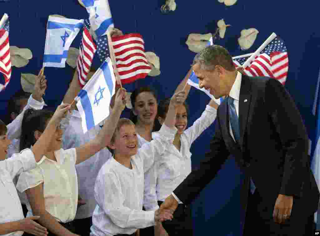 U.S. President Barack Obama shakes hands with Israeli children as he is welcomed by Israeli President Shimon Peres, unseen, in Jerusalem, March 20, 2013. 