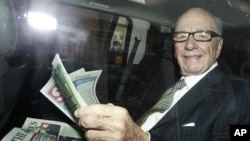 News Corporation CEO Rupert Murdoch holds a copy of The Sun and The Times as he is driven away from his flat in central London July 11, 2011.