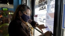 Irma Chavez hangs up a sign in a grocery store as part of her outreach to the immigrant community, Tuesday, March 9, 2021, in Springdale, Arkansas.