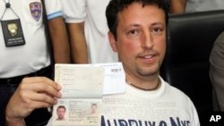 Italian Luigi Maraldi, left, whose stolen passport was used by a passenger boarding a missing Malaysian airliner, shows his passport as he reports himself to Thai police at Phuket police station in Phuket province, southern Thailand, March 9, 2014. 