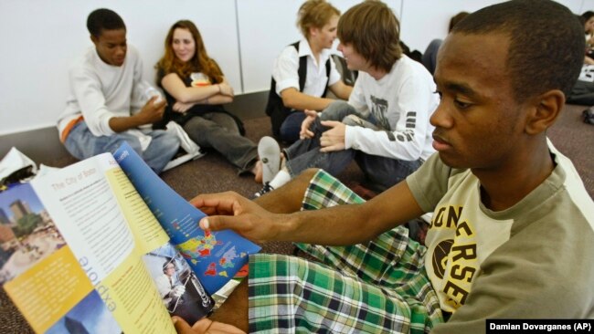 FILE - A high school student from Arleta, California reads information about possible college choices at the National College Fairs event held in Pasadena, California in 2009.