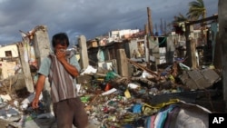 A Filipino man covers his nose from the stench a dead body found at neighborhood badly ravaged by Typhoon Haiyan in Tacloban, Philippines, Saturday, Nov. 16, 2013.