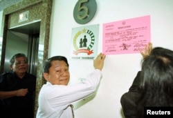 Jaksa dari Kejaksaan Agung menempelkan pengumuman penyitaan di gedung perkantoran Jakarta yang merupakan rumah bagi beberapa yayasan amal Soeharto pada 21 Juli. (Foto: Reuters)