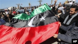 Anti-Libyan leader Moammar Gadhafi protesters wave the old Libyan flag as they celebrate the freedom of the Libyan city of Benghazi, Libya, February 28, 2011