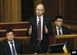 Ukrainian Prime Minister Arseniy Yatsenyuk, center, reacts after surviving a vote of no confidence, in Parliament in Kyiv, Ukraine, Tuesday, Feb. 16, 2016.
