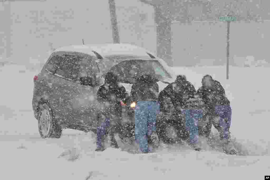 People help push a stranded motorist stuck in deep snow on Stefko Boulevard, Feb. 13, 2014 in Bethlehem, Pennsylvania. 