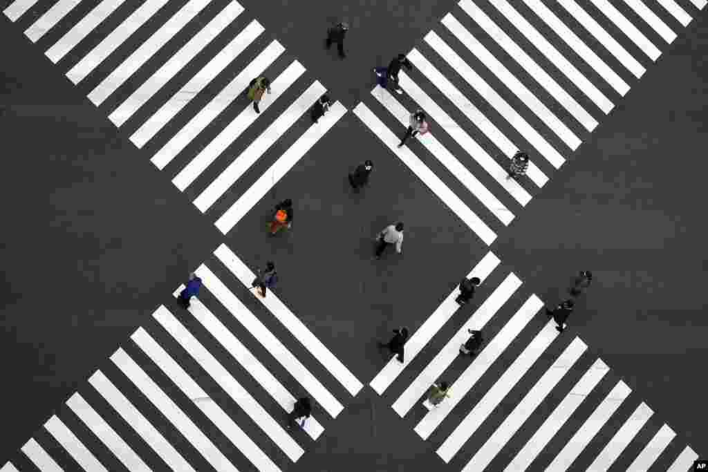 People wearing protective masks to help curb the spread of the coronavirus walk along pedestrian crossings in the Ginza shipping area of Tokyo.