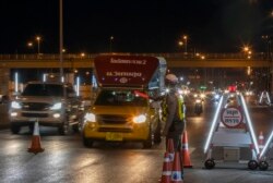 Seorang polisi memberi sinyal pada kendaraan untuk berhenti di pos pemeriksaan di perbatasan provinsi Samut Sakhon dan Bangkok, di Thailand, Senin, 4 Januari 2021.