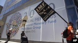 Protesters carry placards and an effigy of a shark outside the International Monetary Fund (IMF) headquarters building during the annual IMF-World Bank meeting, Washington, 8 Oct. 2010.