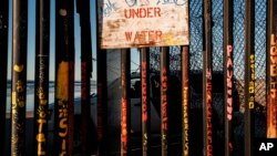 A border patrol office inside his vehicle guards the border fence at the U.S. side of San Diego, Calif., as seen from Tijuana, Mexico, Jan. 2, 2019. 