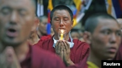 Tibetan monks pray during a candlelight protest march.