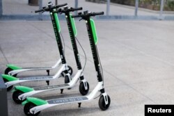 Smart phone app time-of-use electric scooters from Lime-S are shown parked along a sidewalk in San Diego, California, May 17, 2018.