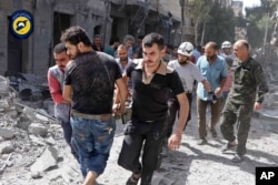 In this photo provided by the Syrian Civil Defense White Helmets, rescue workers work the site of airstrikes in al-Mashhad neighborhood in the rebel-held part of eastern Aleppo, Syria, Sept. 21, 2016.