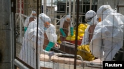 FILE - British health workers lift a newly admitted Ebola patient onto a wheeled stretcher in to the Kerry town Ebola treatment center outside Freetown, Sierra Leone, Dec. 22, 2014.