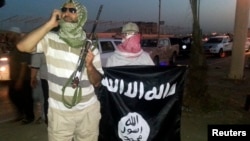 FILE - Militan ISIS memajang bendera kelompok tersebut di kota Mosul, Irak. 