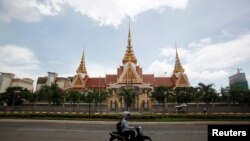 FILE: A man rides a motorcycle past the National Assembly in Phnom Penh August 26, 2014. Cambodia's opposition on Tuesday boosted its influence in a parliament long controlled by the ruling party, winning a deputy chairman post and assurances of greater legislative sway under a deal to end a year-long political impasse. The election of Kem Sokha as deputy house speaker is one of a slew of concessions by Prime Minister Hun Sen seldom seen during his three-decade grip on politics, reflecting the opposition's newfound power and growing public discontent with an authoritarian premier. REUTERS/Samrang Pring (CAMBODIA - Tags: POLITICS ELECTIONS) 