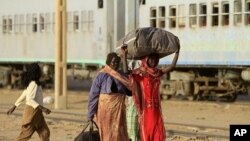 Southern Sudanese family walks towards a train to be transported back to Baher Al Gazal State in South Sudan, in Khartoum, 09 Jan 2011.