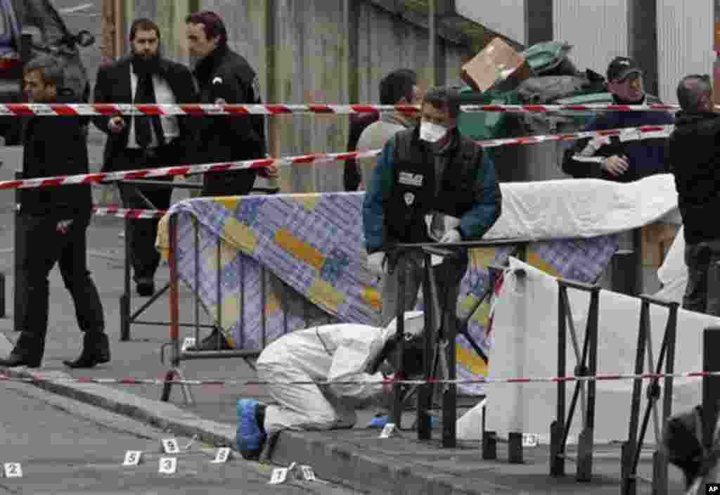 Police officers gather at the site of a shooting in Toulouse, southwestern France, Monday, March 19, 2012. A father and his two sons were among four people who died Monday when a gunman opened fire in front of a Jewish school in a city in southwest France