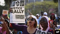 Female residents hold up images of black teenager Trayvon Martin and a packet of Skittles candy during a rally demanding justice for his killing in Miami, Florida April 1, 2012. 