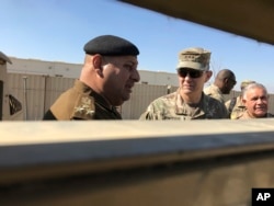 FILE - U.S. Army Lt. Gen. Stephen Townsend, center right, speaks with an Iraqi officer during a visit to an area north of Baghdad, Feb. 8, 2017.