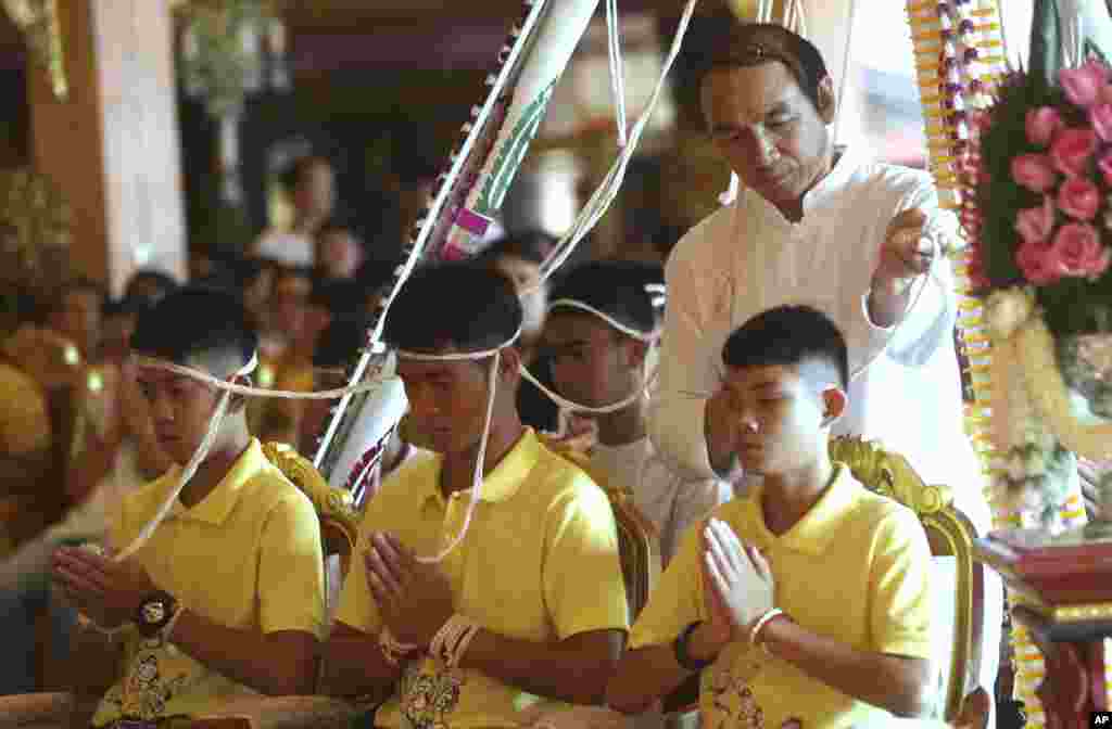 Coach Ekkapol Janthawong, center, and members of the rescued soccer team attend a Buddhist ceremony that is believed to extend the lives as well as ridding them of dangers and misfortunes in Mae Sai district, Chiang Rai province, northern Thailand.