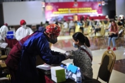 Seorang petugas kesehatan menyuntik warga dengan vaksin Sinovac dalam vaksinasi massal di Semarang pada 22 Juni 2021. (Foto: AFP/Daffa Ramya Kanzuddin)