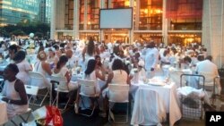 FILE - Guests wearing white clothing sit down to a pop-up dinner at New York's Lincoln Center, Tuesday, Aug. 22, 2017. The event, known as Diner en Blanc, French for Dinner in White, is an annual foodie tradition and began in Paris 29 years ago. (AP Photo)