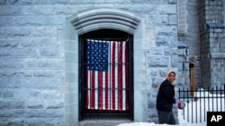 A U.S. flag hangs at the Franco American Heritage Center as a woman enters to attend the local high school's pre-prom fashion show in Lewiston, Maine, Thursday, March 16, 2017.