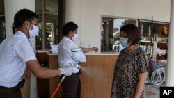 ရန်ကုန်မြို့ စားသောက်ဆိုင်တဆိုင် အဝင်၀ ဝင်လာသူတွေကို ပိုးသတ်ဆေးဖျန်းနေတဲ့ စားသောက်ဆိုင် ဝန်ထမ်းတဦး