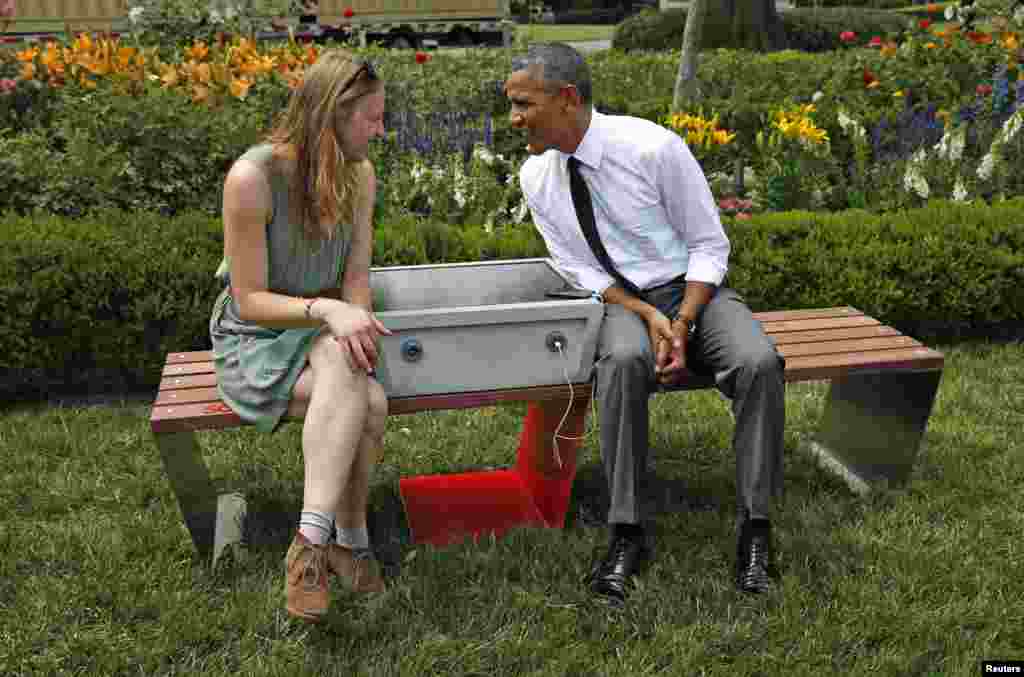 U.S. President Barack Obama speaks with eco-friendly urban furniture designer Sandra Richter while hosting the first-ever White House &quot;Maker Faire&quot; in Washington, D.C., June 18, 2014. The solar-powered bench allows people to charge their phones while resting.