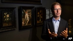Rijksmuseum director Taco Dibbits, standing in front of Bartholomeus Spanger's "Body of Christ Supported by Angels" oil on copper painting, center, discusses the gift of the major painting which went on display in Amsterdam, Netherlands, June 1, 2020. (AP Photo/Peter Dejong)