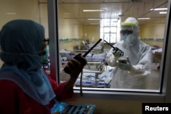 Pekerja kesehatan berbicara melalui walkie-talki di ruang isolasi untuk pasien virus corona (Covid-19) di Rumah Sakit Persahabatan, Jakarta, 13 Mei 2020. (Foto: Reuters)