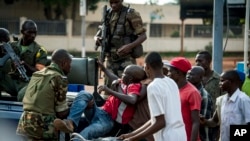 FILE: African Union Misca forces from Cameroon carry a wounded man as angry youth set up barricades throughout the town, May 29, 2014 in Bangui, Central African Republic. 