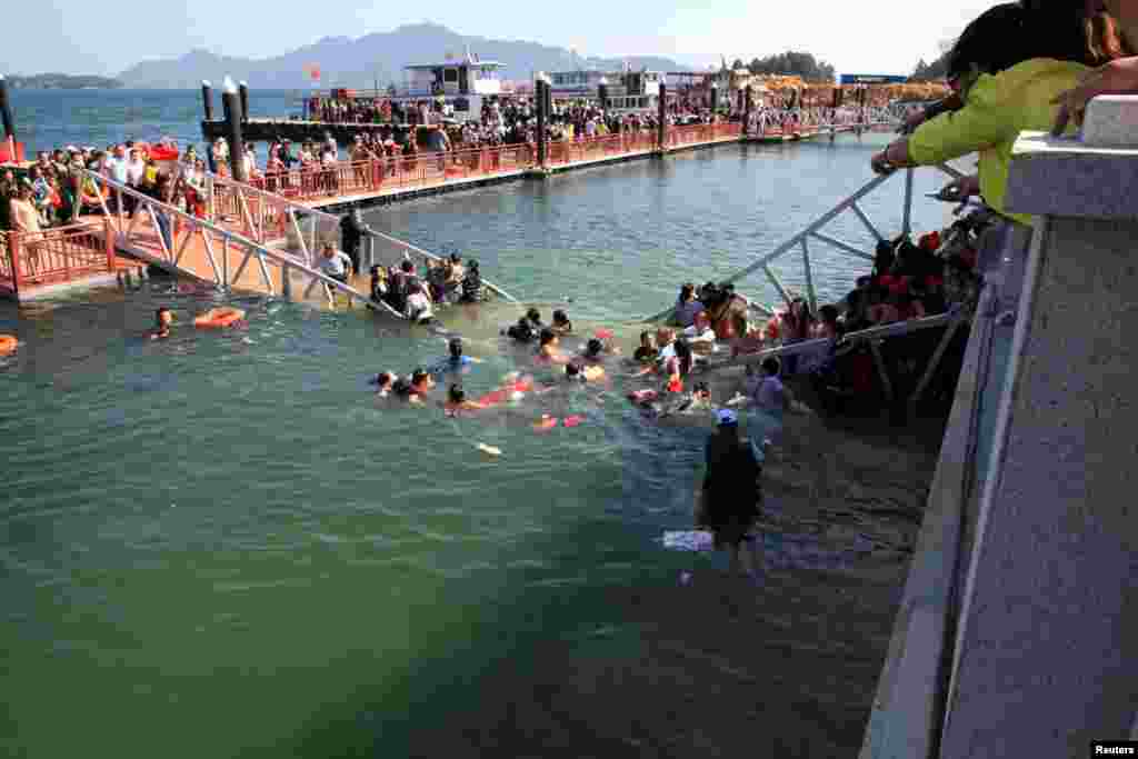 Bystanders point to tourists fallen into water after a newly-built bridge collapsed due to excessive weight capacity at Lushan Mountain, Jiangxi province, China, Oct. 13, 2013.