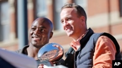 Denver Broncos quarterback Peyton Manning and defensive end DeMarcus Ware hold the Lombardi Trophy during a parade for the NFL football Super Bowl champions in Denver, Feb. 9, 2016.