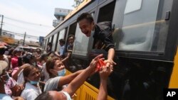 Seorang narapidana berupaya menyalami keluarganya dari dalam bus, setelah dibebaskan dari penjara Insein di Yangon, Myanmar, 17 April 2020.