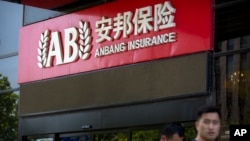 People walk past an entrance to the Anbang Insurance Group's offices in Beijing, June 14, 2017. 