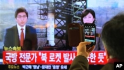 12일 한국 서울역에서 북한의 장거리 로켓 발사 소식을 지켜보는 주민.