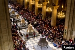 FILE - People attend a ceremony to bless the new eight bronze bells of Notre-Dame de Paris Cathedral in Paris, France, Feb. 2, 2013.