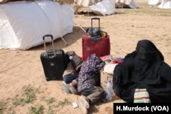A woman, not knowing when or where she is going, waits with her children behind a collection of tents. "I don't know who I'm supposed to be afraid of, but I am afraid," she says, near Baghuz in Deir el-Zour, Syria, Feb. 26, 2019. (H.Murdock/VOA)