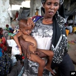 An internally displaced woman holds her malnourished son at a new settlement in Somalia's capital Mogadishu, July 19, 2011.