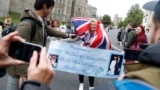 A Royal fan carrying a banner is interviewed by a member of the media, outside Windsor Castle in Windsor, south England, Monday May 6, 2019, after Prince Harry announced that his wife Meghan, Duchess of Sussex, has given birth to a boy. (AP Photo/Alastair Grant)