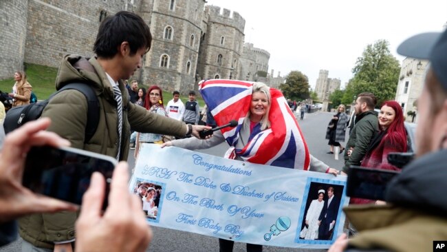 Un fanático de la realeza Royal lleva una pancarta en las afueras del Castillo de Windsor en Windsor, sur de Inglaterra, el lunes 6 de mayo de 2019, después de que el príncipe Harry anunció que su esposa Meghan, duquesa de Sussex, había dado a luz a un niño.