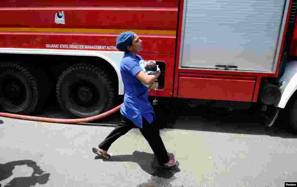 인도&nbsp;아마다바드의 아동 병원의 난간에서 화재가 발생한 후 간호사가 신생아와 함게 대피하고 있다.