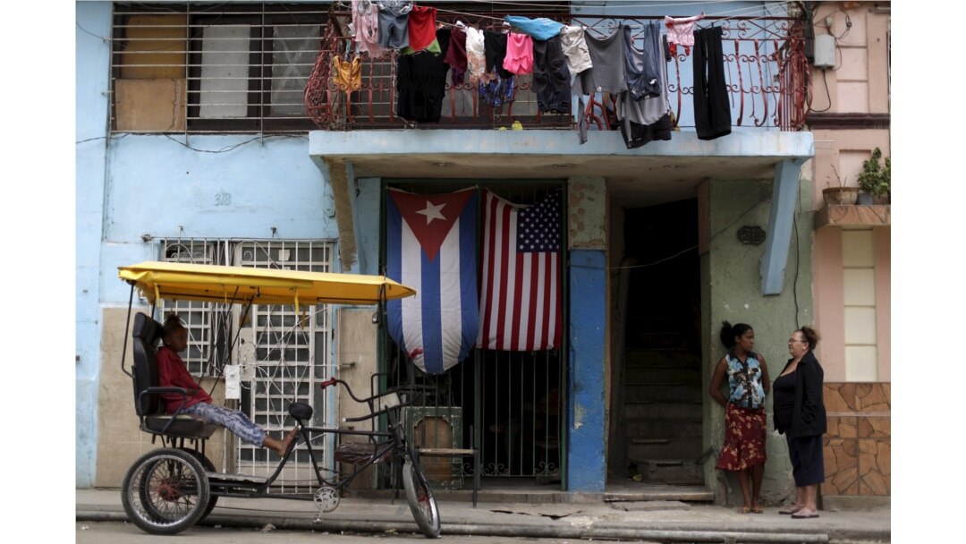 Perempuan terlihat di depan sebuah rumah berhiaskan bendera AS dan Kuba di pinggiran Havana, Kuba 21 Maret 2016. (Foto: REUTERS/Ueslei Marcelino)