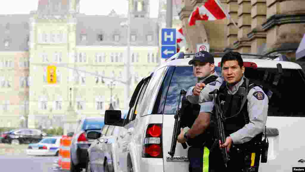 Armed Royal Canadian Mounted Police officers guard access to Parliament Hill following a shooting incident in Ottawa.