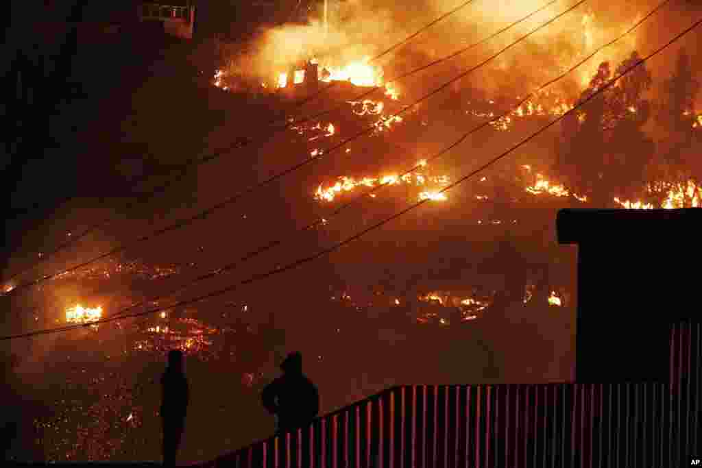 Emergency responders watch as an out of control forest fire destroys homes in the city of Valparaiso, Chile, April 13, 2014. 