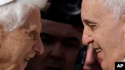 FILE - Pope Emeritus Benedict XVI, left, and Pope Francis exchange greetings at a 2014 meeting. 