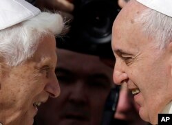 El papa emérito Benedicto XVI, izquierda, y el papa Francisco se saludan durante un encuentro en 2014.