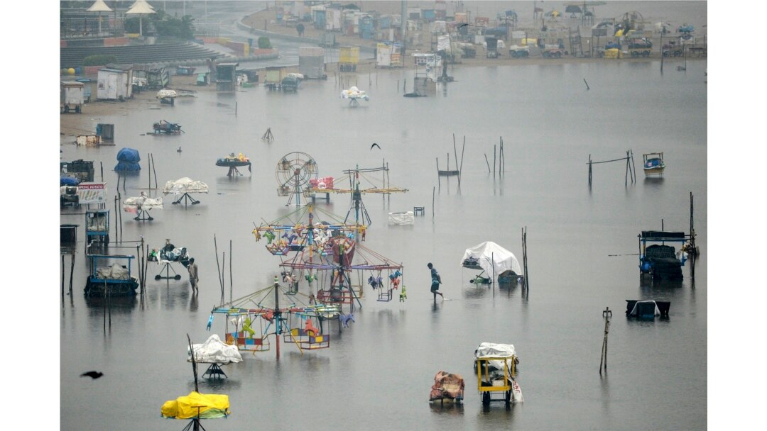 Seorang pria mengarungi bagian pantai Marina yang terendam banjir yang dipicu oleh hujan deras di Chennai, 9 November 2021. (Arun SANKAR / AFP)